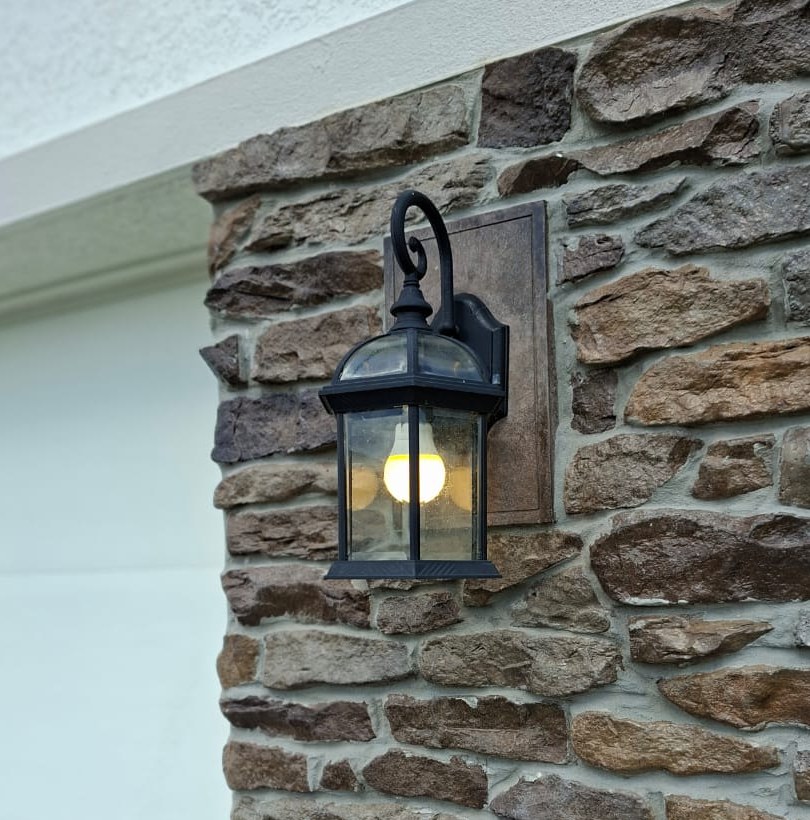 Restored black wall lantern on a stone exterior